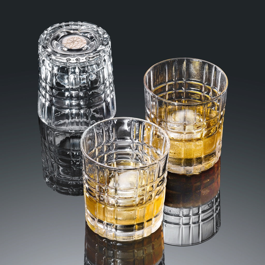 Set aus drei strukturierten Whiskeygläsern mit Whiskey und Eiswürfeln auf spiegelnder Oberfläche in Studioaufnahme-coolglass